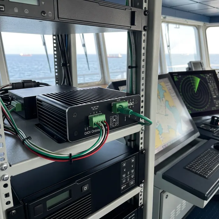 DIDI Onboard Unit mounted on a bridge equipment rack shelf with RS485 and network cabling, radar and ECDIS displays alongside